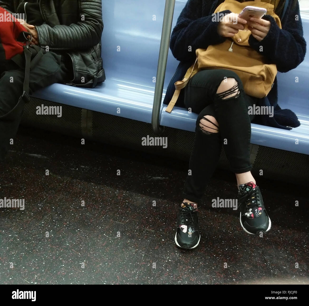 Ein Teenager in der u-Bahn in New York Texte während des Tragens sie modisch zerrissene Jeans, gesehen auf Sonntag, 28. Februar 2016. (© Richard B. Levine) Stockfoto