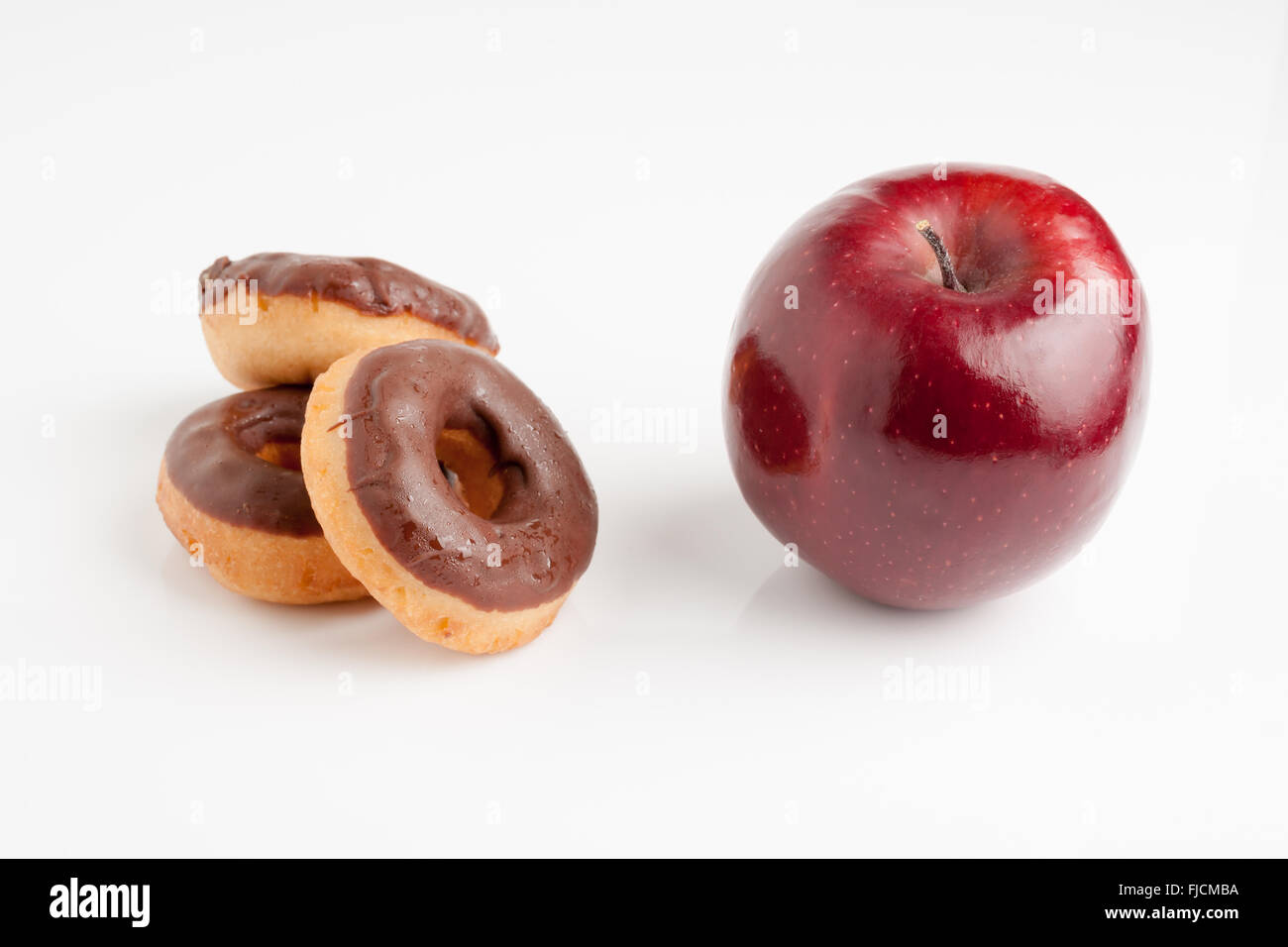 Schokoladen Donuts oder eine schöne gesunde glänzenden roten Apfel Diät oder Junk-Food Konzept Stockfoto