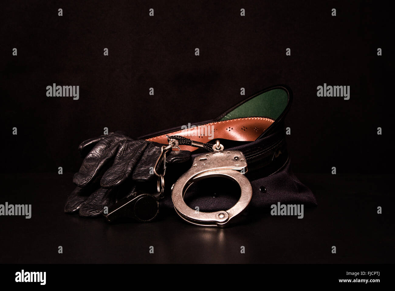 Eine Polizeimütze mit Lederhandschuhe, Pfeifen und Handschellen. Stockfoto