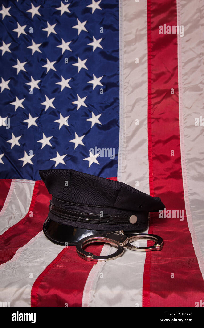 Eine Polizeimütze mit Handschellen an eine amerikanische Flagge Hintergrund. Stockfoto