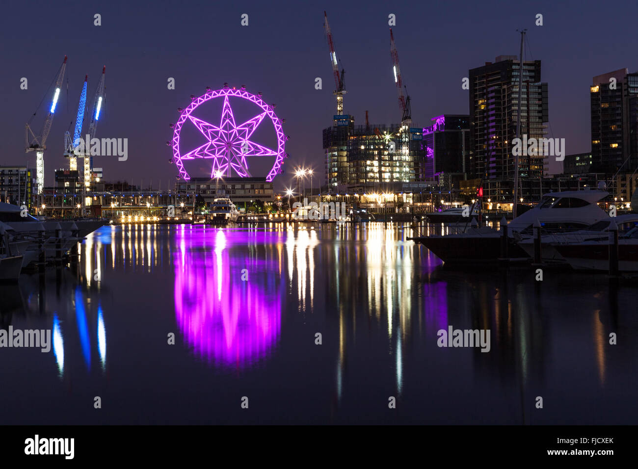 Melbourne, Australien - 21. Februar 2016: Riesenrad beleuchtet in lila in den Docklands, Melbourne mit Reflexionen im Yarra River. Hallo! Stockfoto