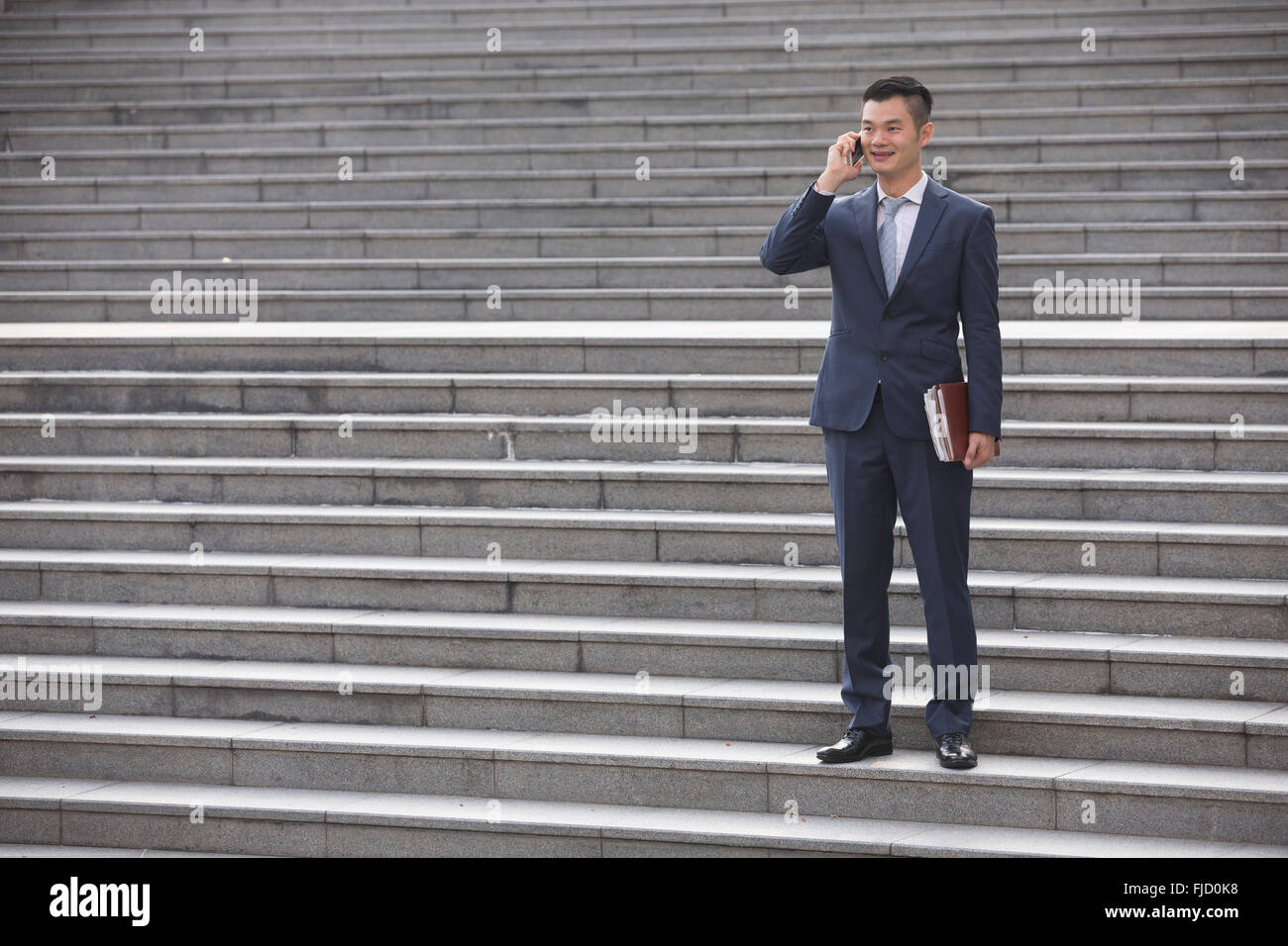 Ein glücklich chinesischen Geschäftsmann mit seinem Smartphone. Stockfoto