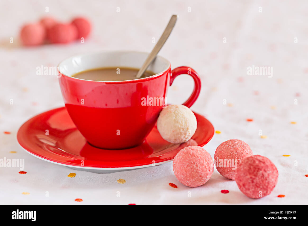 Rote Kaffeetasse mit Süßigkeiten auf Tisch Stockfoto