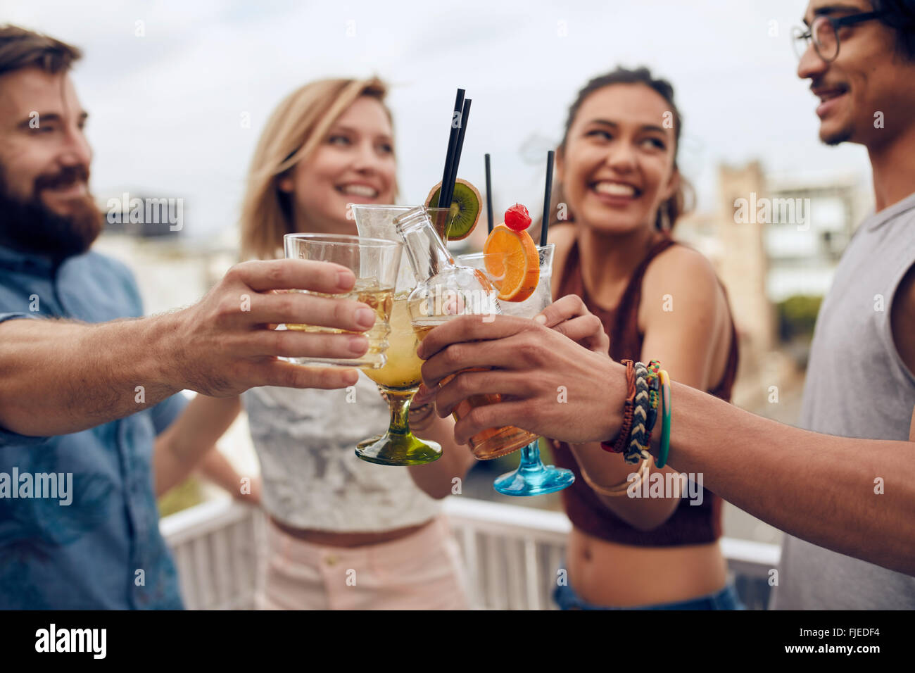 Freunde, Spaß und tranken Cocktails im Freien auf einem Dach zusammenkommen. Gruppe von Freunden rumhängen und Toasten trinkt ou Stockfoto