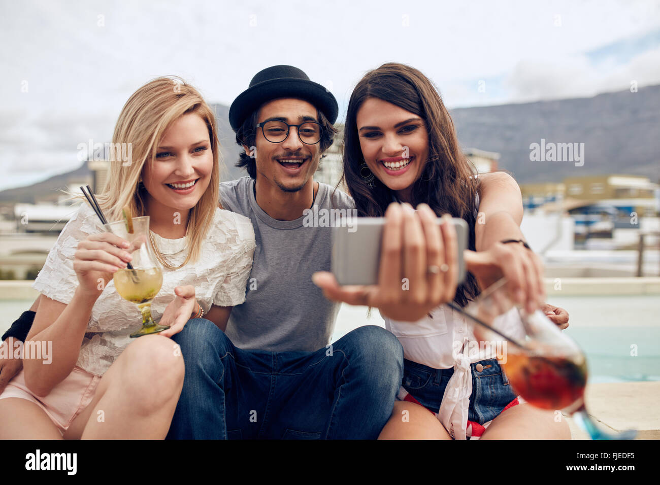 Gruppe von Freunden nehmen Selfie auf einem Smartphone. Junger Mann und Frauen mit Getränken, wobei ein Selbstporträt auf Handy. Junge Menschen Stockfoto