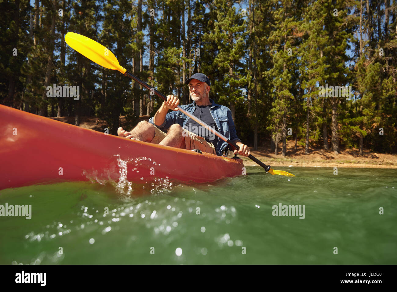 Porträt von reifer Mann eine Kajak in einem See paddeln. Senior kaukasischen Mann Kanu an Sommertag. Stockfoto