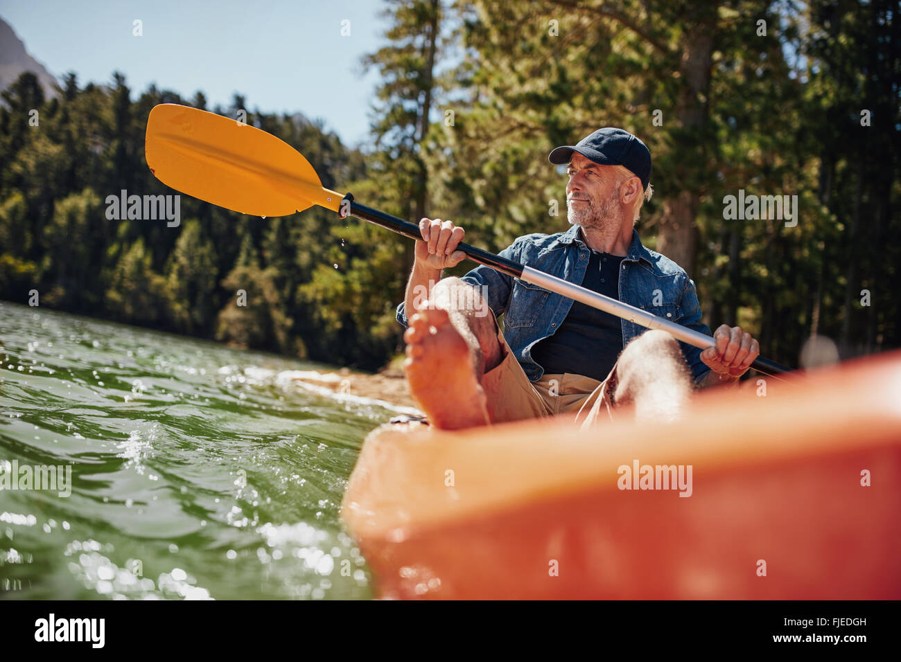 Porträt von einem reifen Mann mit Kajak in einem See. Kaukasischen Mann paddeln eine Kajak an Sommertag. Stockfoto