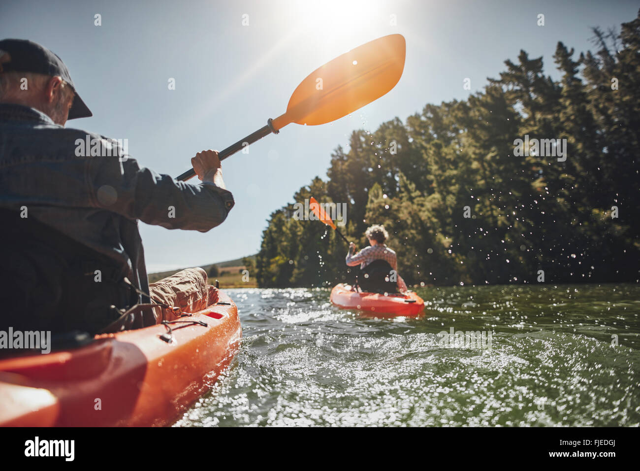 Im Freien Schuss von senior woman Kanu im See mit Frau im Hintergrund an einem Sommertag. Mann und Frau in zwei verschiedenen Kajaks Stockfoto