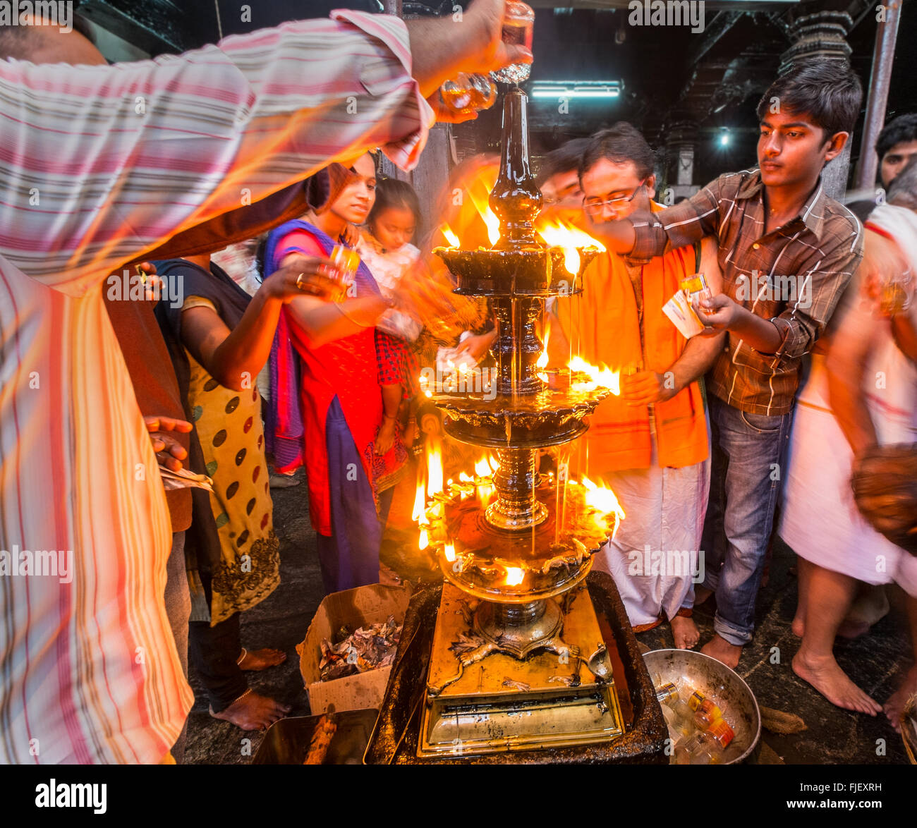 Anhänger gießen Öl auf eine heilige Flamme in einem Tempel in Udupi, Indien Stockfoto