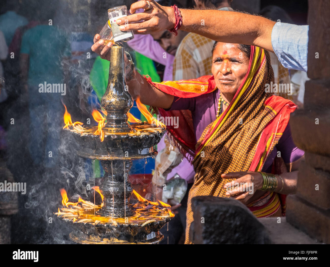 Hindus gießen Öl auf eine heilige Flamme in einem Tempel in Udupi, Südindien Stockfoto