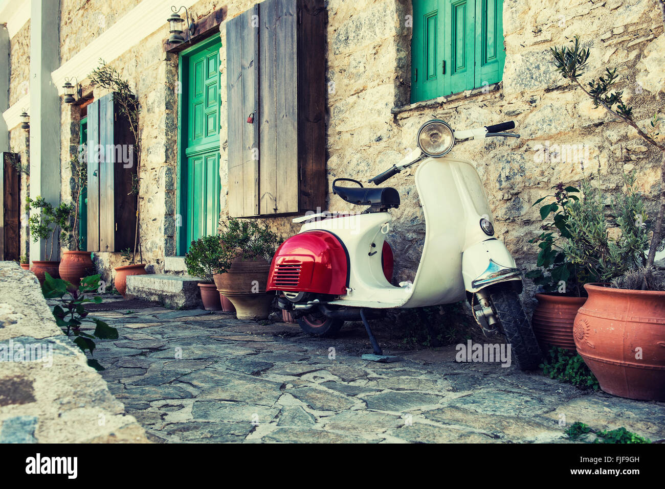 Karpathos, Griechenland - 10. Oktober 2015: Alte Scooter parkte vor der Wand in die leere Straße von Karpathos, Griechenland. Stockfoto