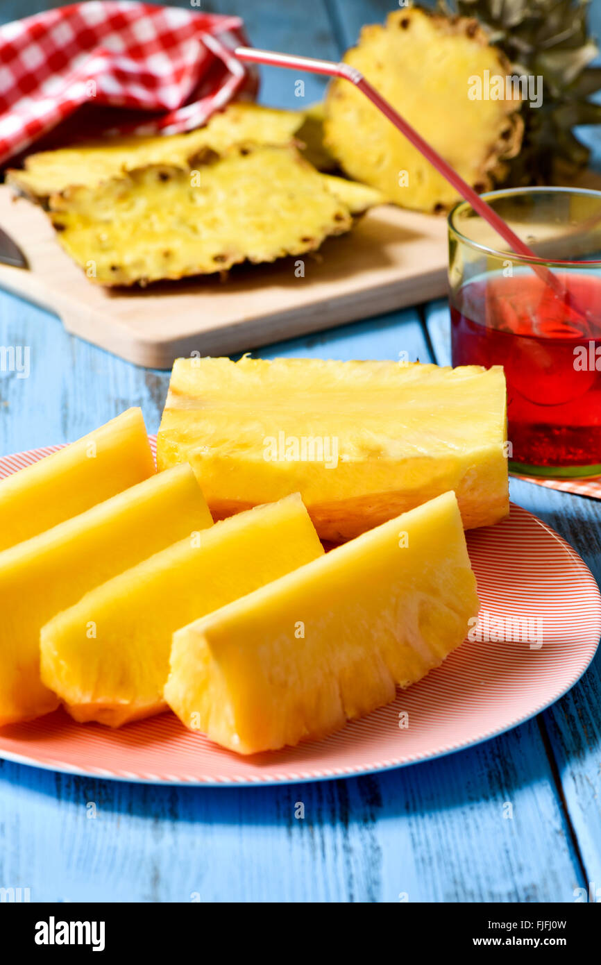 Nahaufnahme einer Platte mit frisch Ananas schneiden auf einem blauen rustikalen Holztisch Stockfoto