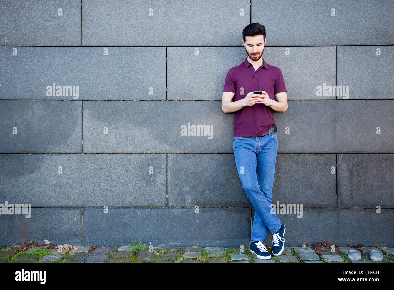 Porträt von einem attraktiven jungen Mann mit Smartphone Stockfoto