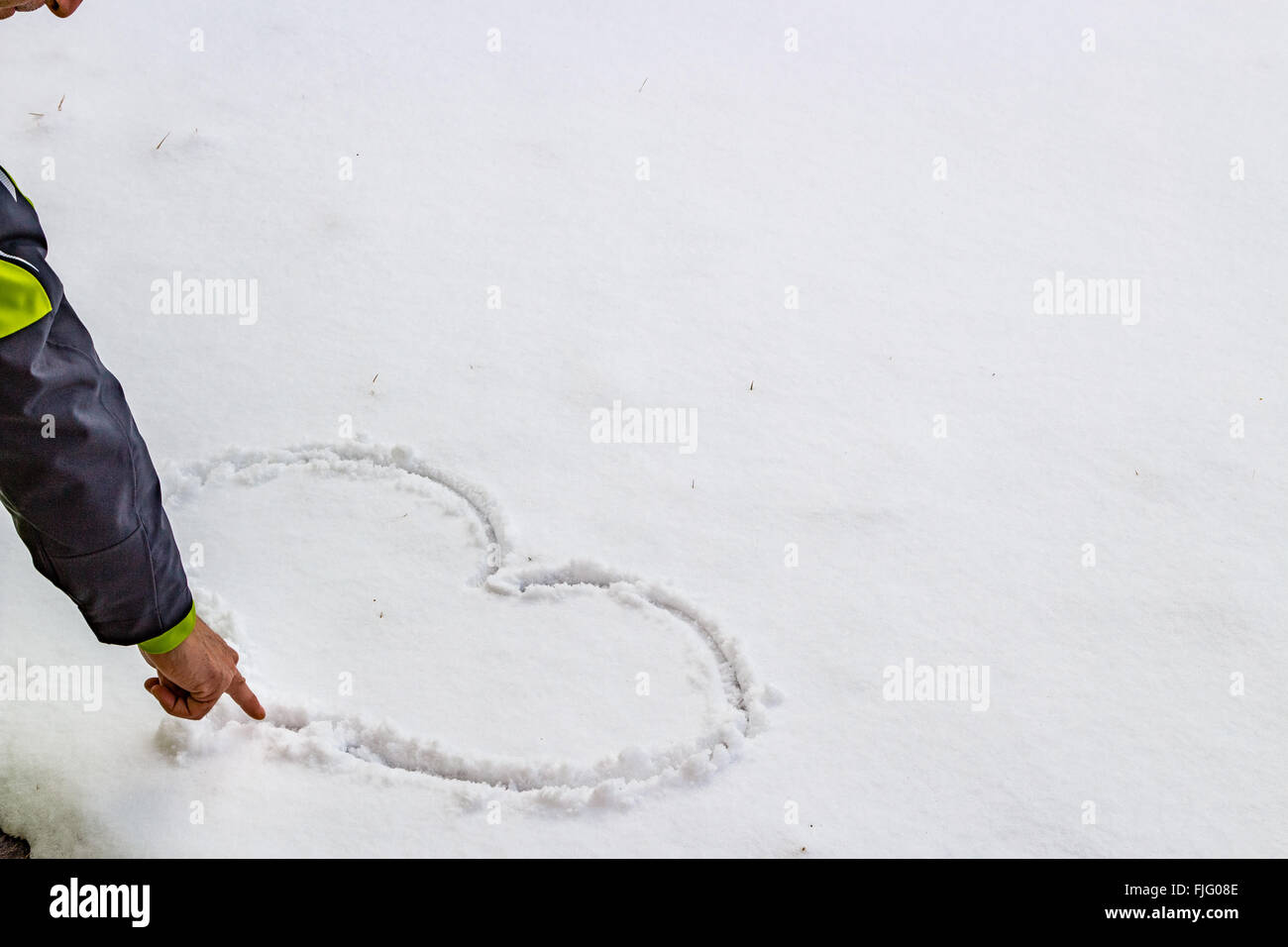 Hand eines Mannes, der ein Herz in den Schnee zeichnen ist Stockfoto