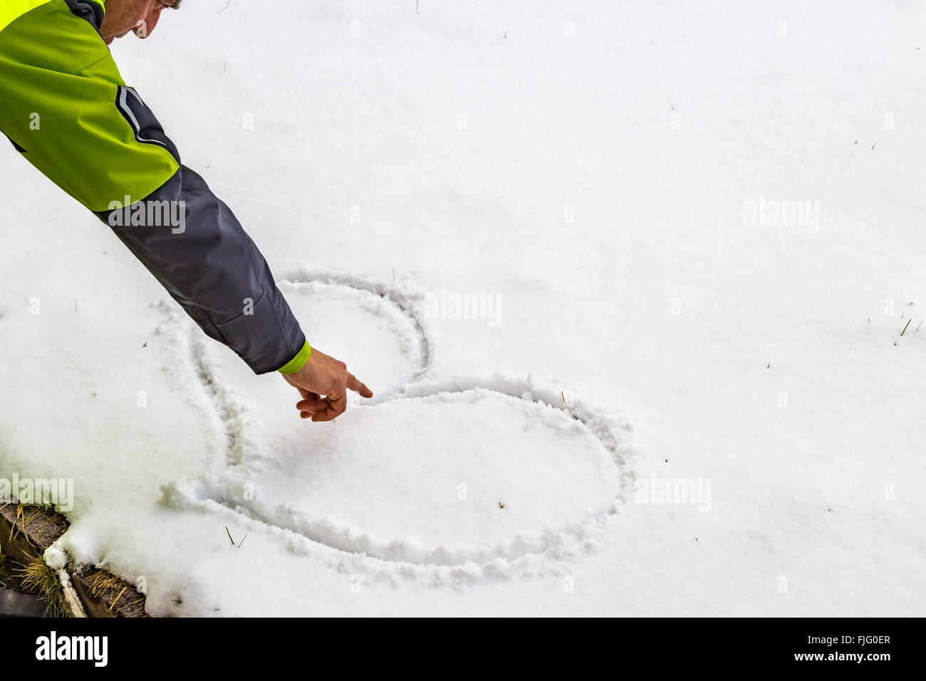 Hand eines Mannes, der ein Herz in den Schnee zeichnen ist Stockfoto