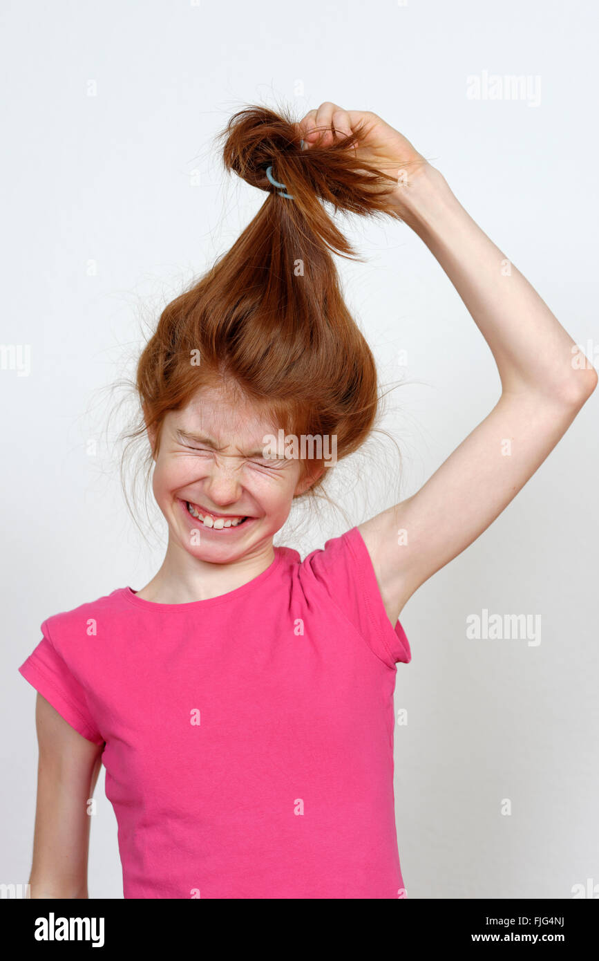 Mädchen mit langen roten Haaren ziehen ihr Haar binden, Bayern, Deutschland Stockfoto