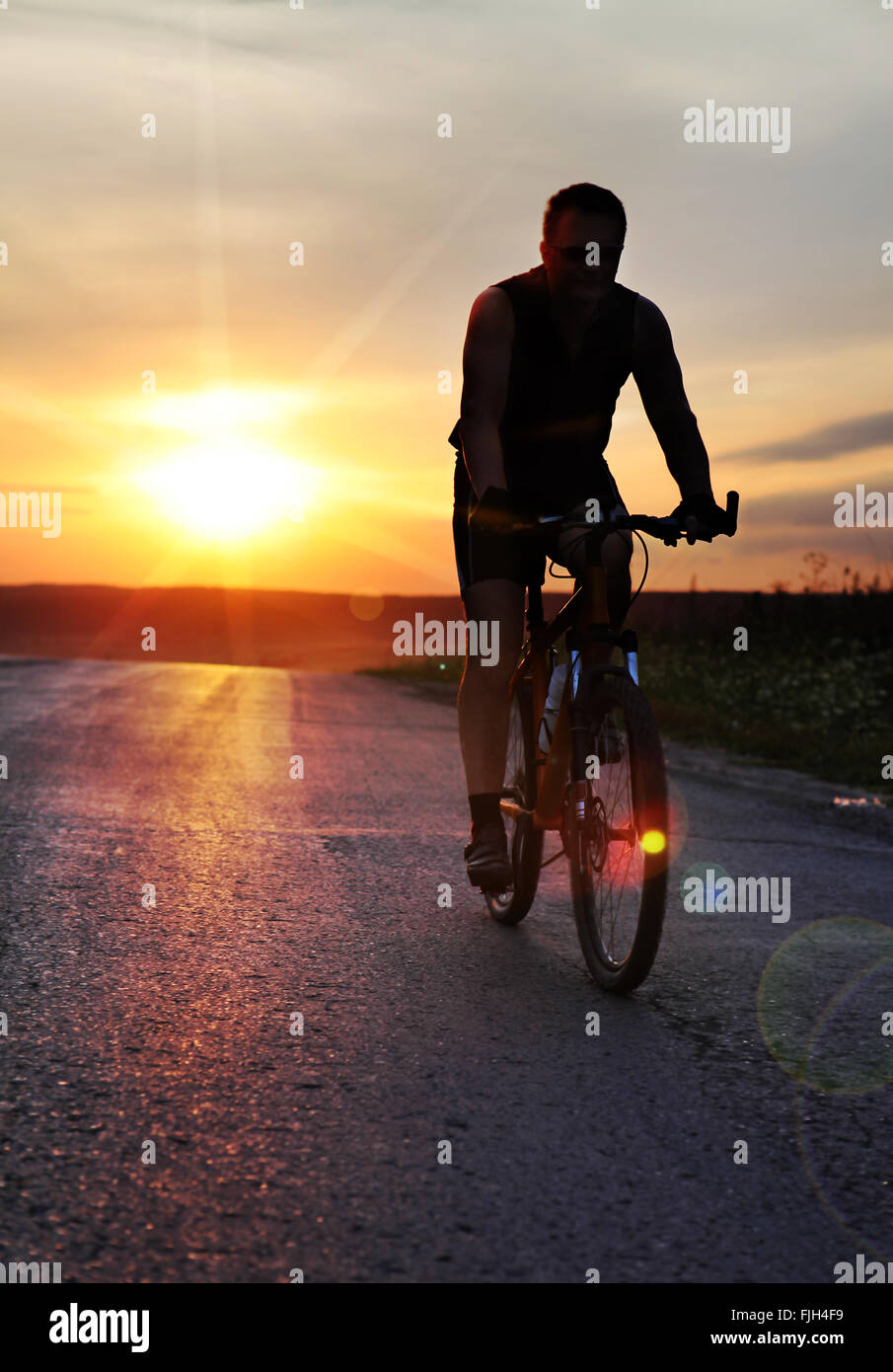Reisende mit Fahrrad gestoppt auf Feld bei Sonnenuntergang Stockfoto