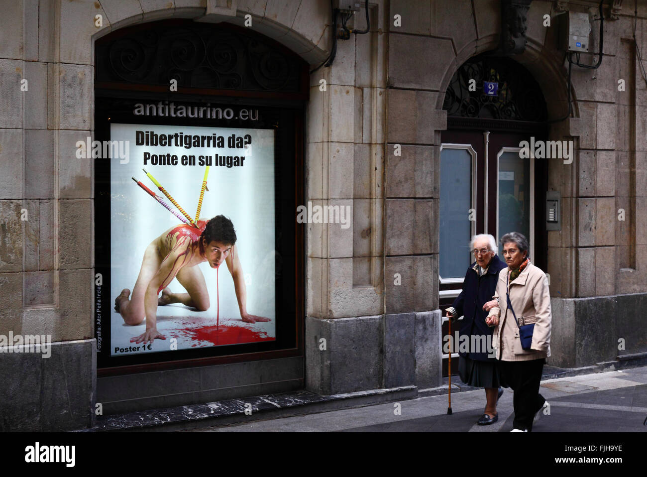 Menschen zu Fuß vorbei an einem Plakat im Fenster protestieren gegen Stierkampf, Casco Viejo, Bilbao, Baskenland, Spanien Stockfoto