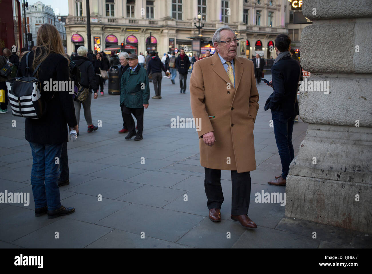 Gentleman trägt einen Kamelen Mantel verwandelt sich eine Ecke aus Piccadilly Circus in central London, UK. Stockfoto