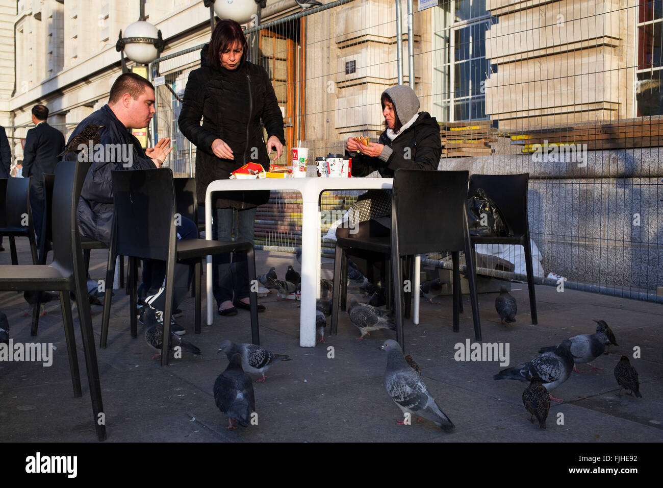 Touristen vor McDonalds sind von hungrigen Tauben belagert, die bummeln rund um für Krümel und direkt angreifen das Essen auf dem Tisch. South Bank, London, UK. Stockfoto