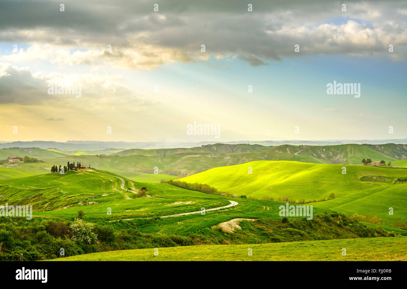 Toskana, Sonnenuntergang Landschaft im ländlichen Raum. Landschaft Bauernhof, Zypressen Bäume, grüne Wiese, Sonnenlicht und Cloud. Volterra, Italien, Europa. Stockfoto
