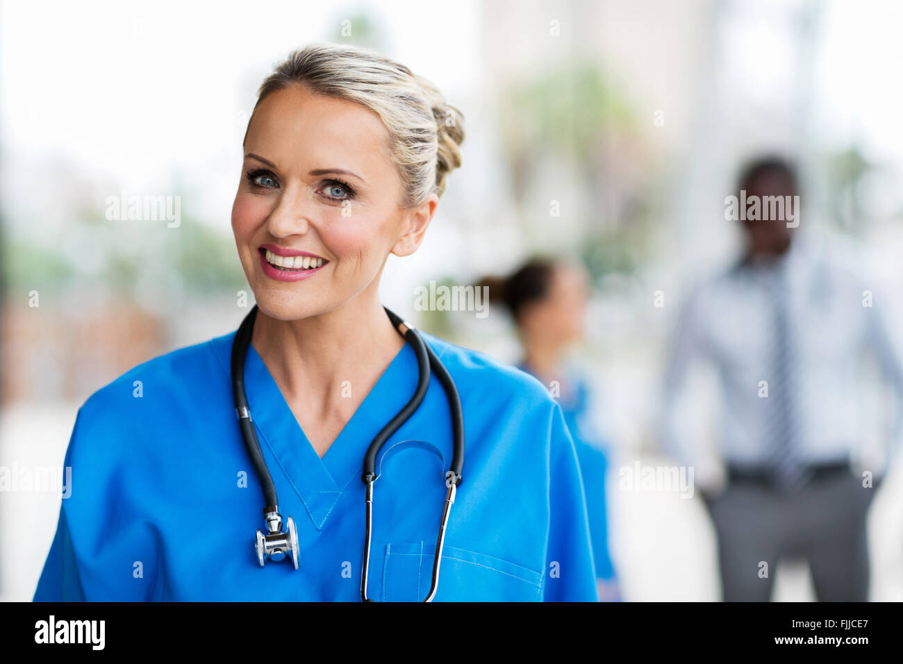 schöne Krankenschwester mit Kolleginnen und Kollegen im Hintergrund Stockfoto