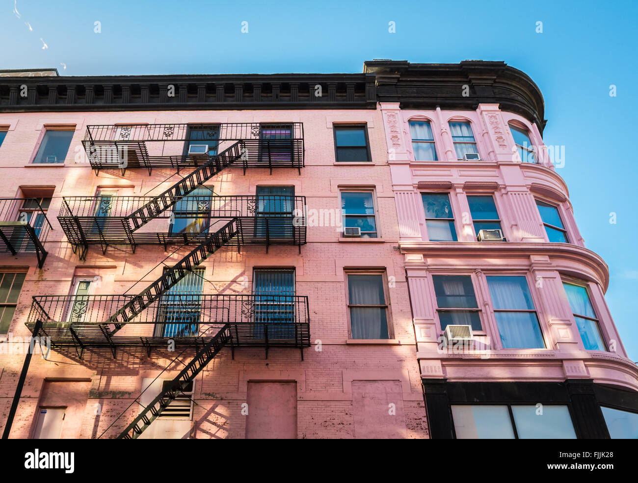 Rosa altes traditionelles Gebäude in New York City mit Metall Feuerleitern an der Fassade. Stockfoto