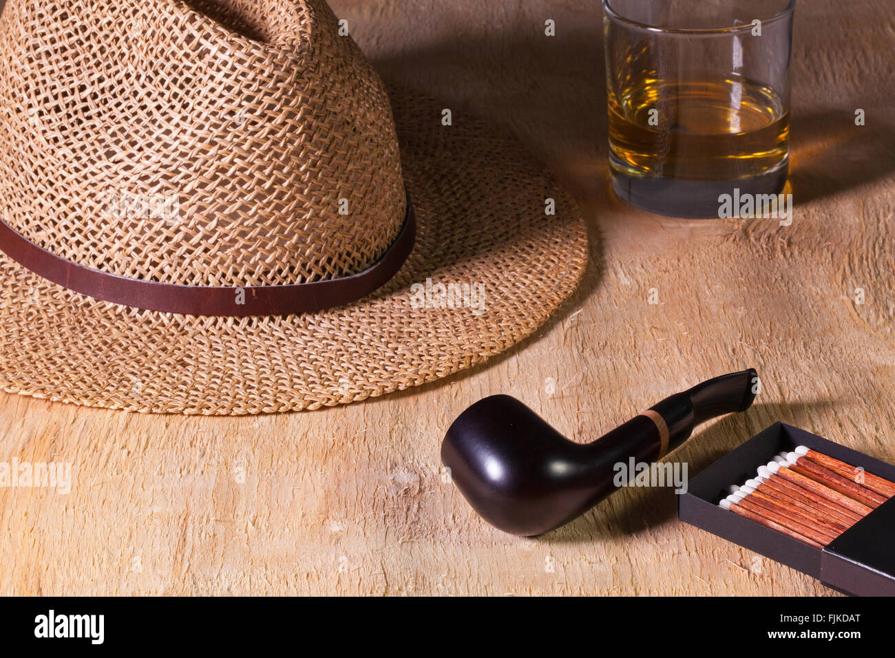 Siesta - Rohr, Strohhut und Scotch Whisky auf einem Holztisch Stockfoto