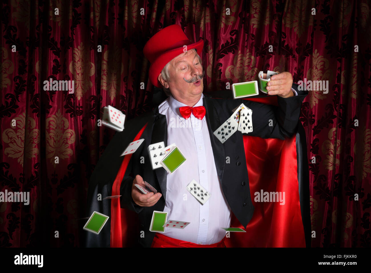 Reife Magier auf der Bühne einen Zaubertrick mit Karten Stockfoto