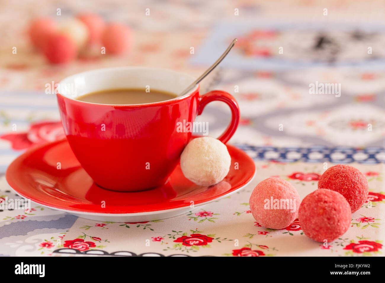 Rote Kaffeetasse mit Süßigkeiten auf Tischdecke Stockfoto