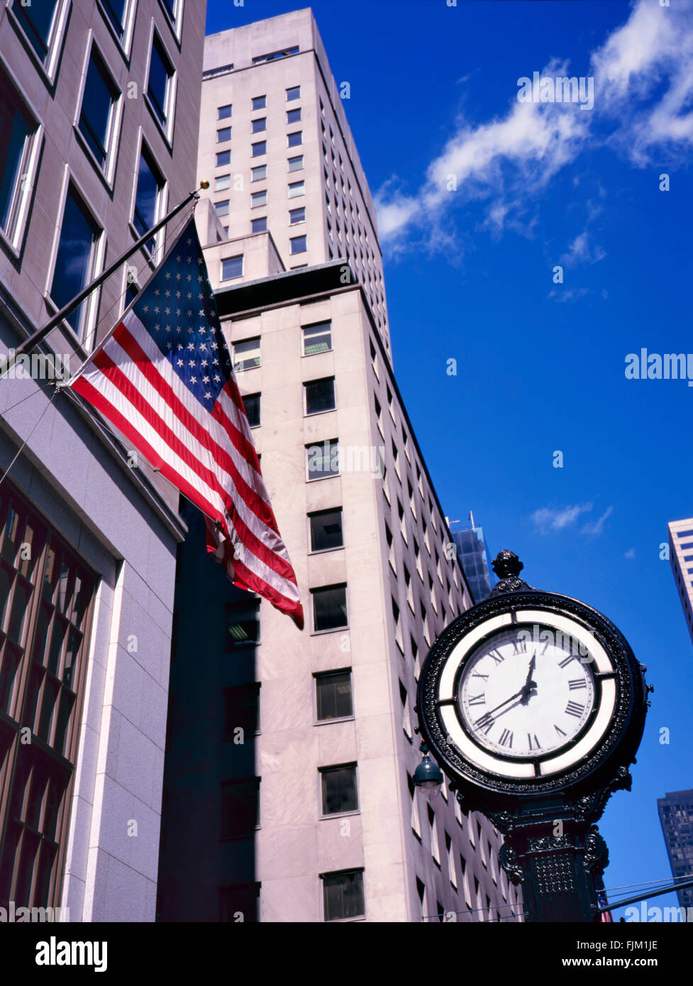 Klassischen Stil Uhr auf der Fifth Avenue in Manhattan, New York, USA. Die amerikanische Flagge am Gebäude Stockfoto