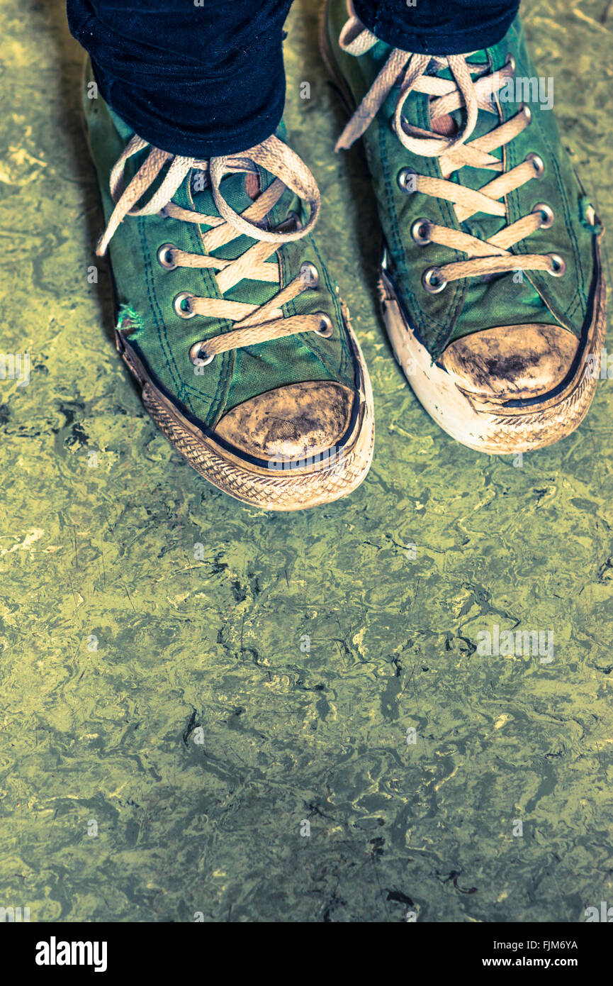 grüne Turnschuhe gegen grünliche Boden Stockfoto