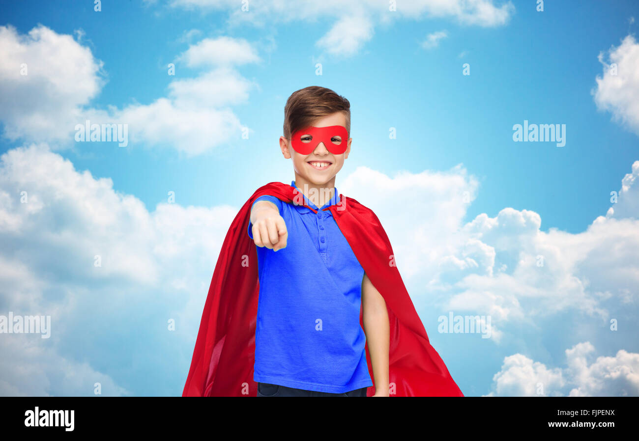 fröhlicher Junge im roten Superhelden Cape und Maske Stockfoto