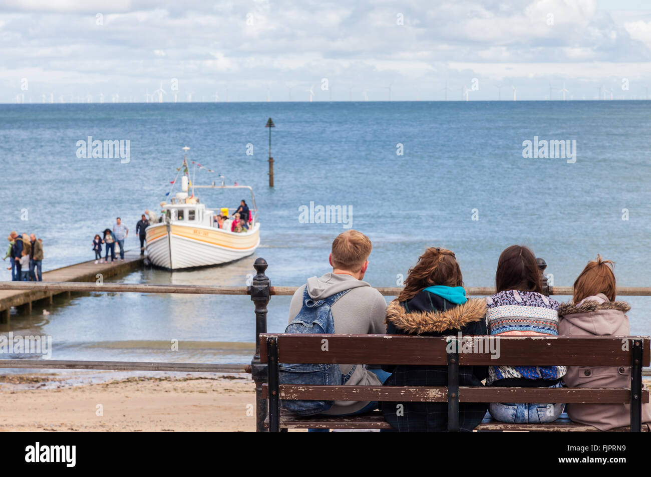 Junge Familie sitzt entspannt Blick auf das Meer genießen Sie die Landschaft als Vergnügungsschiff Boot kehrt mit Touristen. Stockfoto