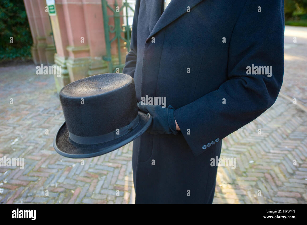 Eine Begräbnis-Führer mit einem Hut in der Hand wartet auf einem Friedhof Stockfoto