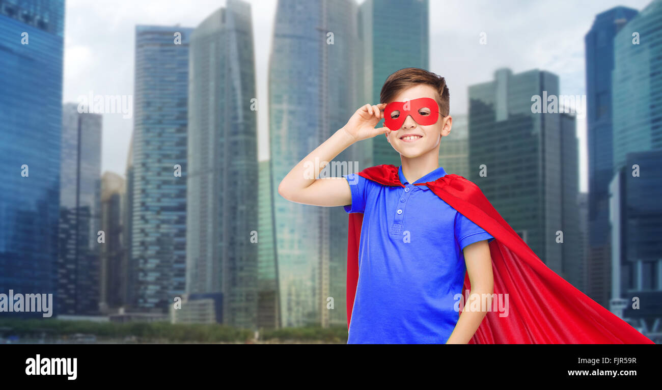 Junge im roten Superhelden Cape und Maske Stockfoto