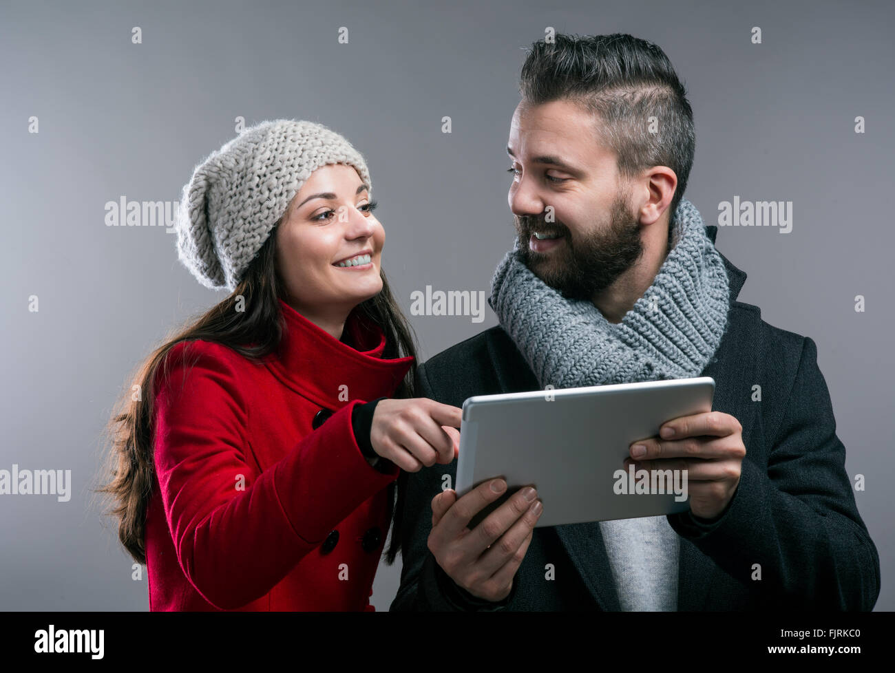 Junge Frau und Mann in Winterjacken mit tablet Stockfoto