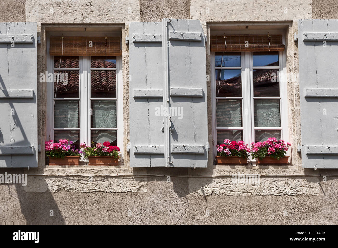 Fenster mit Fensterläden aus Holz und hübsch blühende Balkonkästen Stockfoto