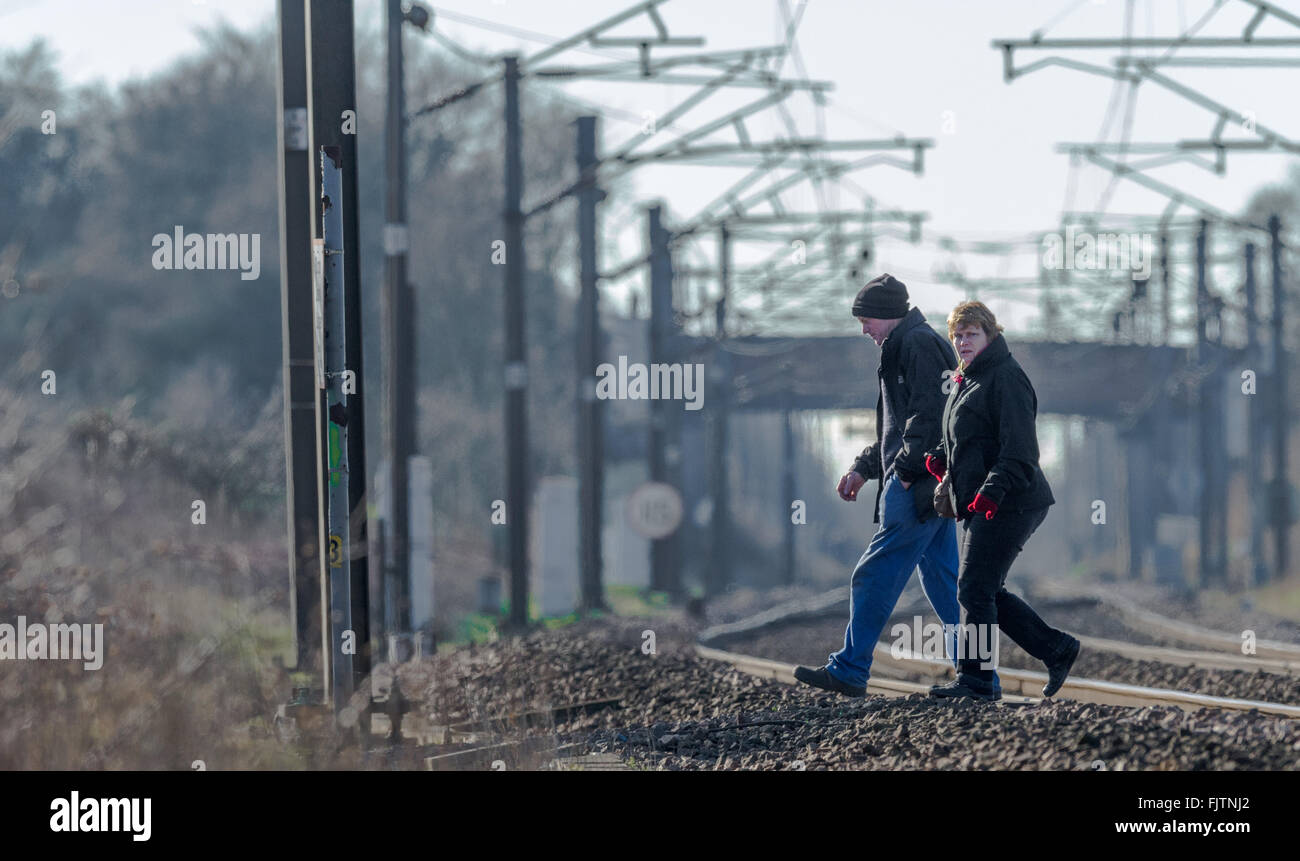 Mann und Frau mit dem Fußgänger Bahnübergang auf der East Coast Main Line in der Nähe von Retford, Nottinghamshire. Stockfoto