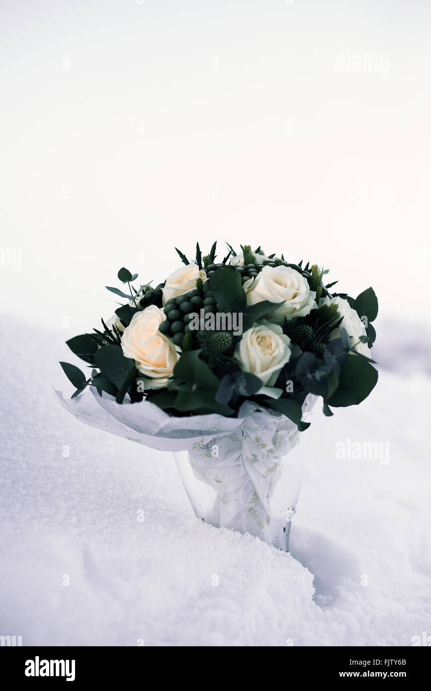 Hochzeitsblumen, Blätter und Rosen in einer Glasvase im Schnee. Stockfoto