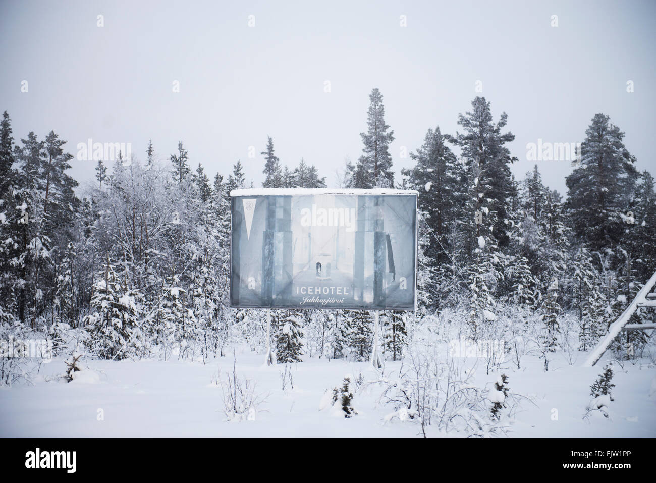 Plakat an der Abzweigung führt zu Jukkasjarvi, Werbung das Ice Hotel, Schweden. mit Schnee und Eis auf den Bäumen Stockfoto