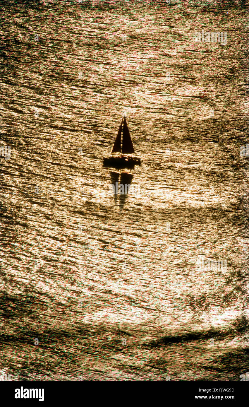 Einflügelige Segelboot auf ruhigen Pazifik vor der kalifornischen Küste mit Sonne, die über die strahlende Oberfläche reflektiert wird Stockfoto