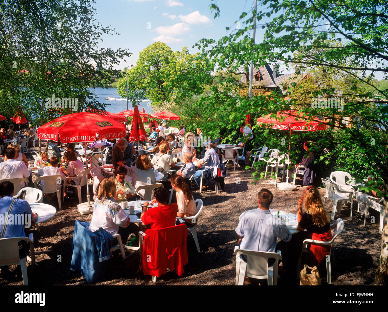 Familien und Besucher bei Cafe Amadeus teilen Sommer essen und Gespräche im malerischen Djurgarden Djurgården Park in Stockholm Stockfoto