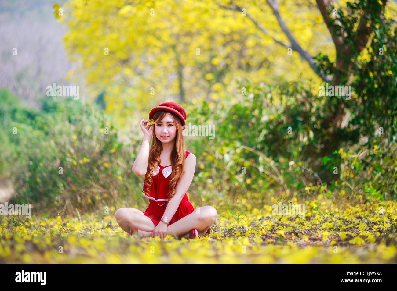 Porträt von einem schönen Mädchen unter den gelben Blüten in der Natur, Thailand, Asien. Stockfoto