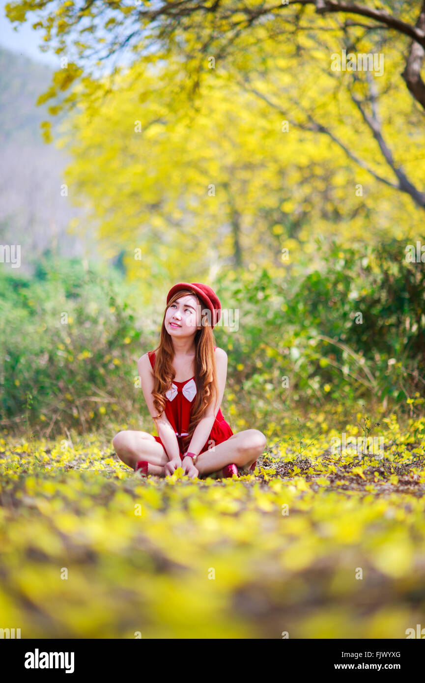 Porträt von einem schönen Mädchen unter den gelben Blüten in der Natur, Thailand, Asien. Stockfoto