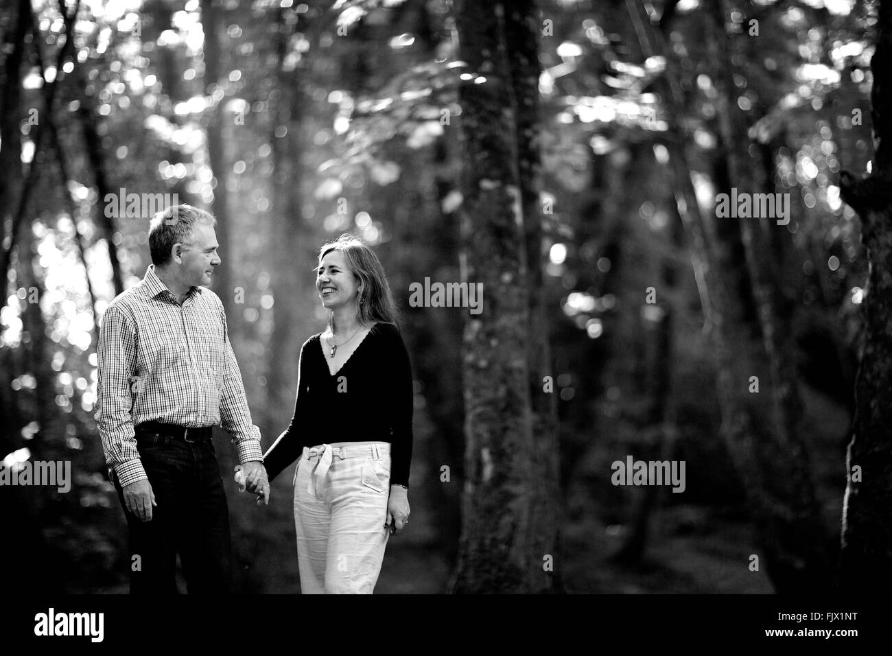 Paar im Wald umgeben von Natur, Hand in Hand, glücklich, Lächeln, in der Liebe Stockfoto