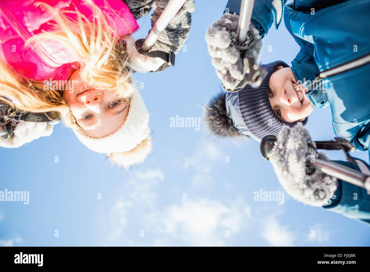 Geschwister halten Skistöcke Stockfoto