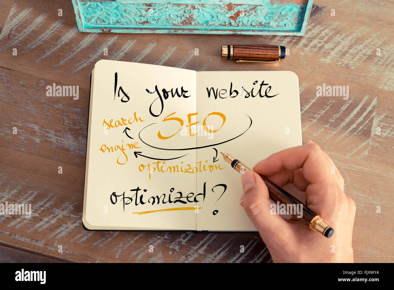 Retro-Effekt und getönten Bild einer Frau hand schreiben eine Notiz mit einem Füllfederhalter auf einem Notebook. Handgeschriebener Text ist Ihre Website SEO optimiert? als Firmen-Konzept-image Stockfoto