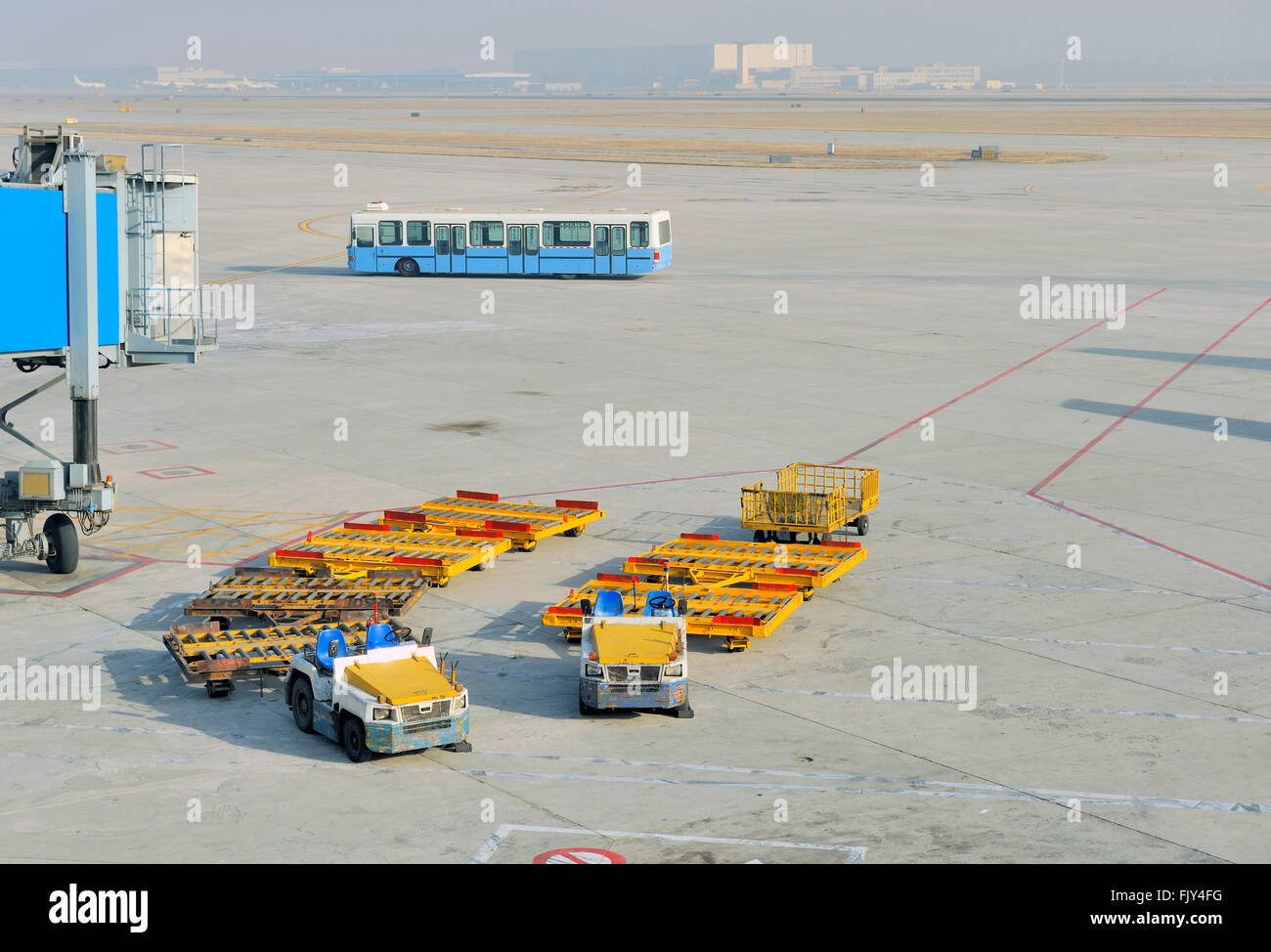 Aircargo Ausrüstung Fahrzeuge auf dem Flughafen; im Hintergrund ein Bus für den Transport der Passagiere Stockfoto
