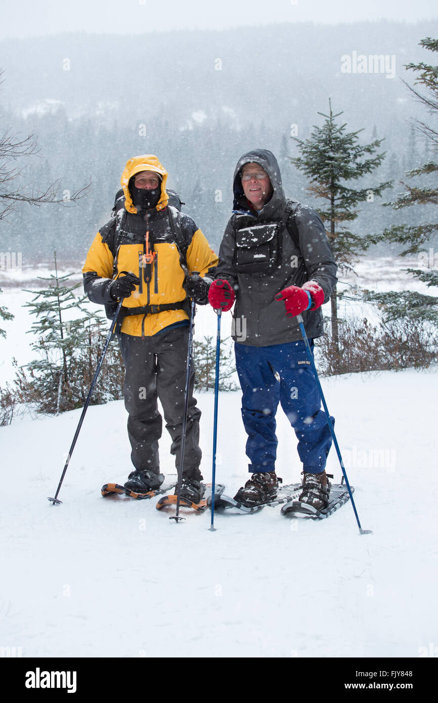 Zwei Senioren Schneeschuh an einem verschneiten Tag in den Wäldern des nördlichen Maine nahe Rangeley. Stockfoto